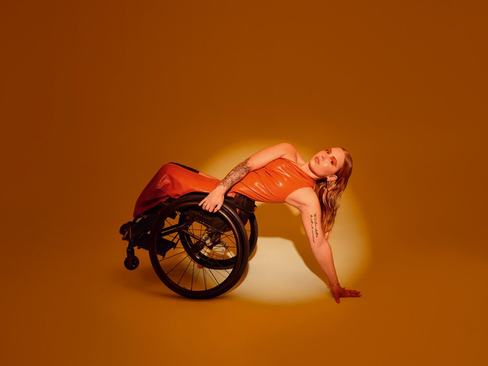 Un véhicule adapté aux personnes à mobilité réduite : la Classe C Break dans une vue de 3/4 arrière et une femme en fauteuil roulant.