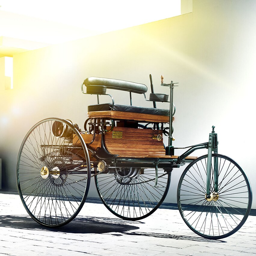 Benz Patent-Motorwagen devant une maison moderne, illustrant les origines de Mercedes-Benz.
