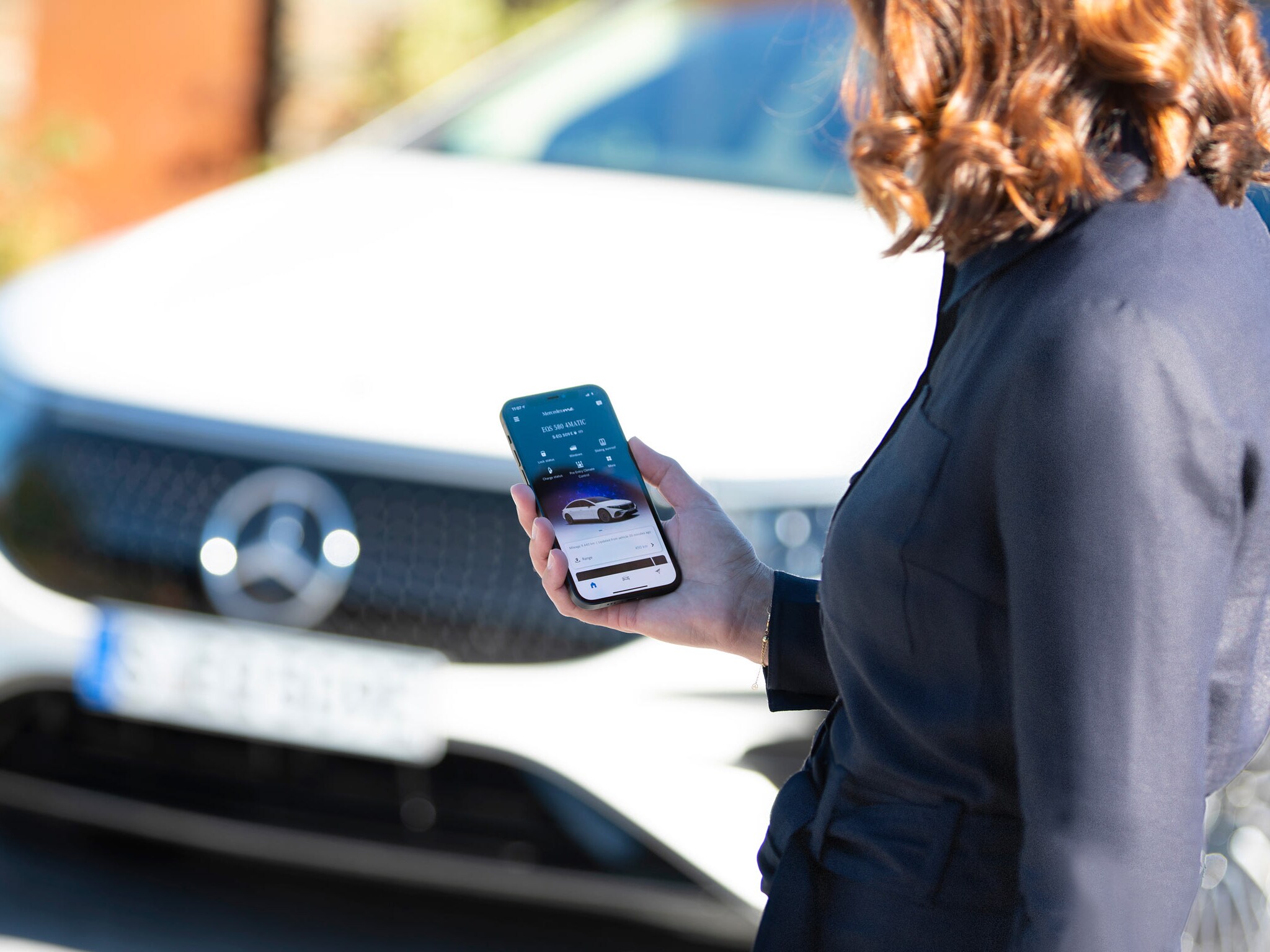 Image d'une femme sur son téléphone portable devant son véhicule
