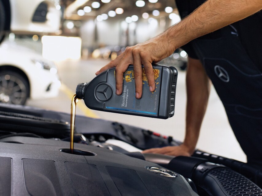 Gros plan sur le compartiment moteur pendant le remplissage avec de l'huile moteur d'origine Mercedes-Benz.
