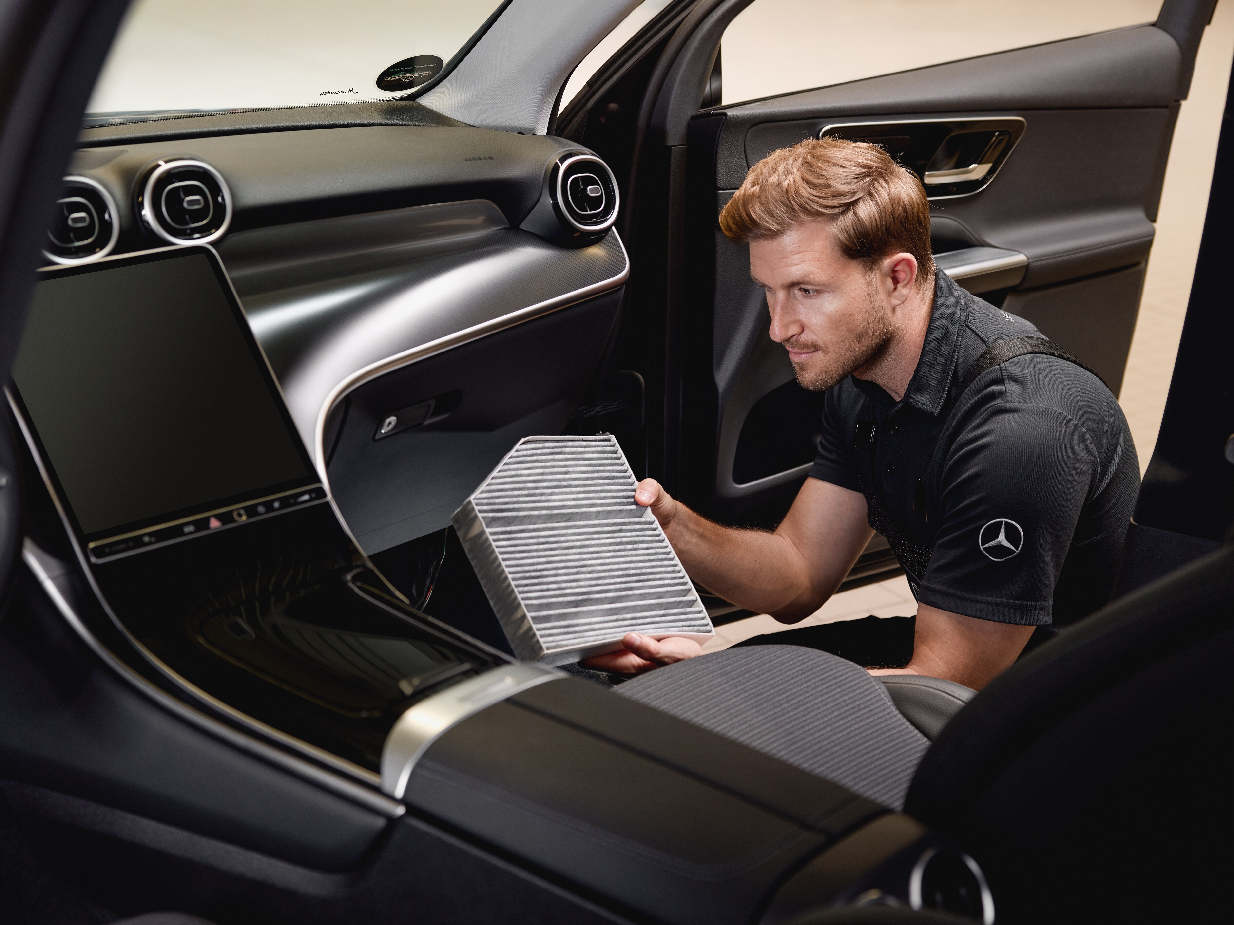 Intervention de maintenance dans l'habitacle montrant le remplacement d'un filtre à air intérieur par une pièce d'origine Mercedes-Benz.