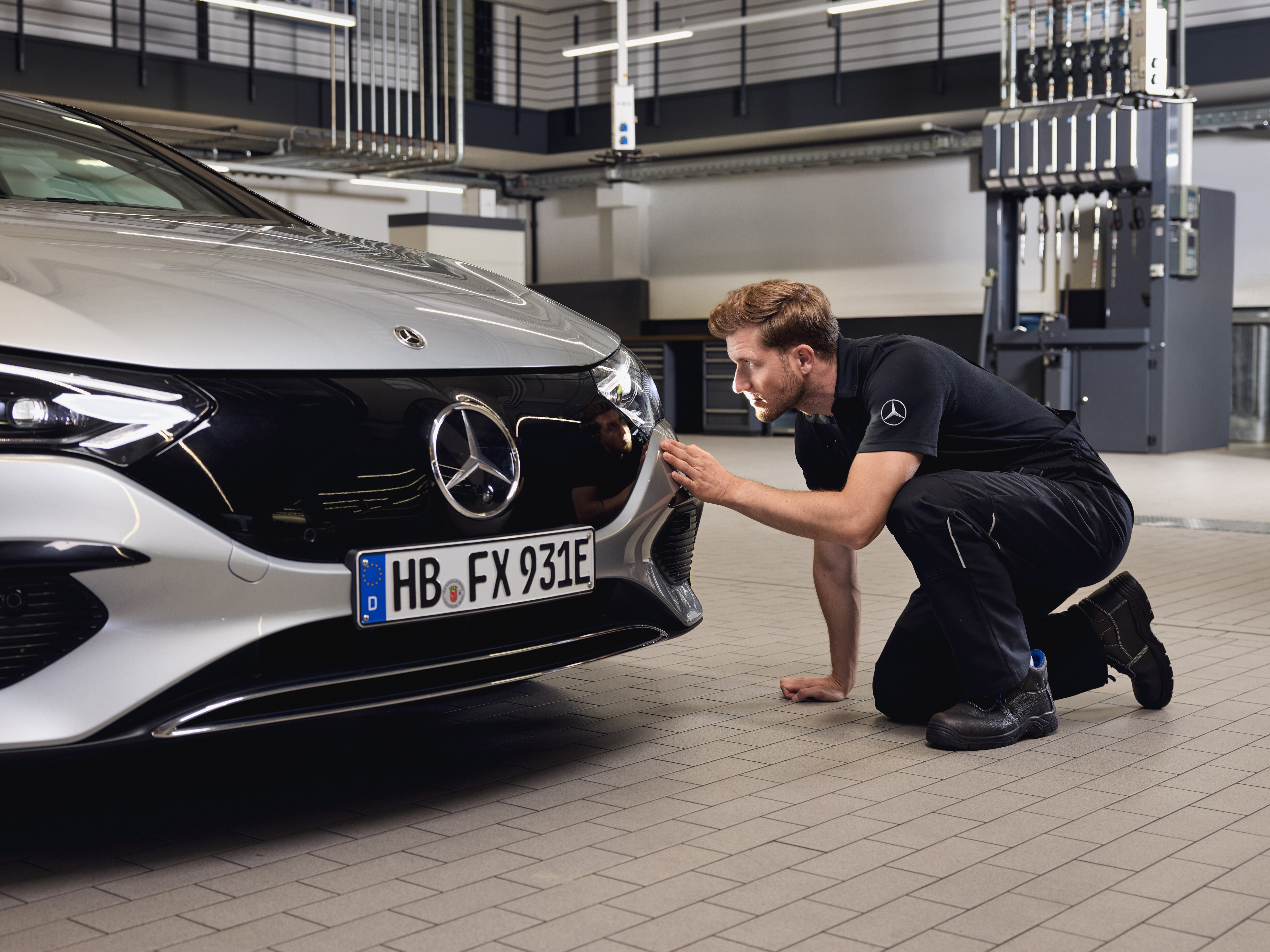 Gros plan sur l'avant d'un véhicule Mercedes-Benz, avec un technicien procédant à un contrôle minutieux lors du remplacement de pièces d'origine Mercedes-Benz.