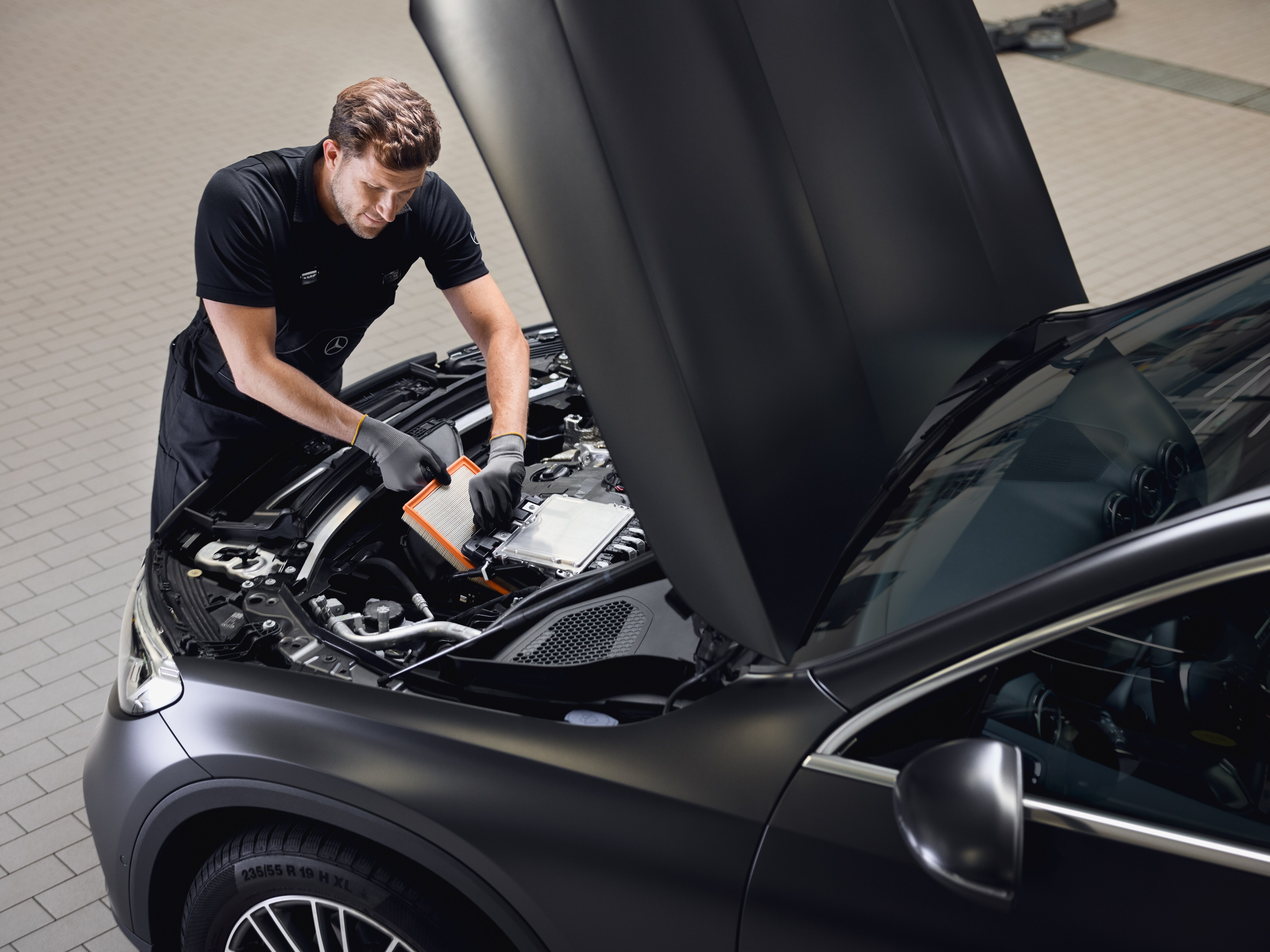 Maintenance du moteur montrant le remplacement d'un filtre à air moteur par une pièce d'origine Mercedes-Benz dans un atelier agréé.