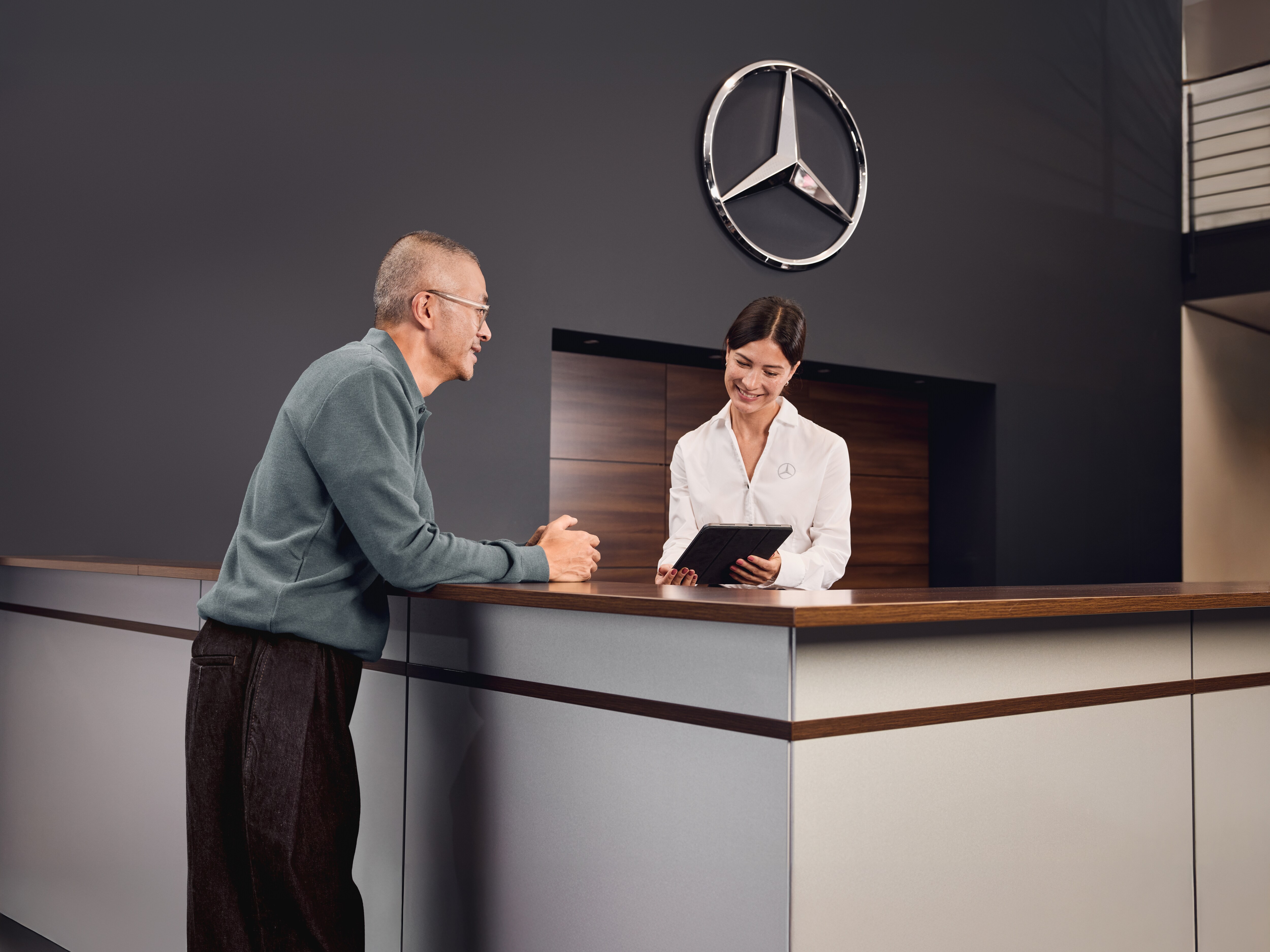 Accueil du service après-vente d'un distributeur Mercedes-Benz, où un client discute des détails de la maintenance de son véhicule avec un conseiller du service après-vente.