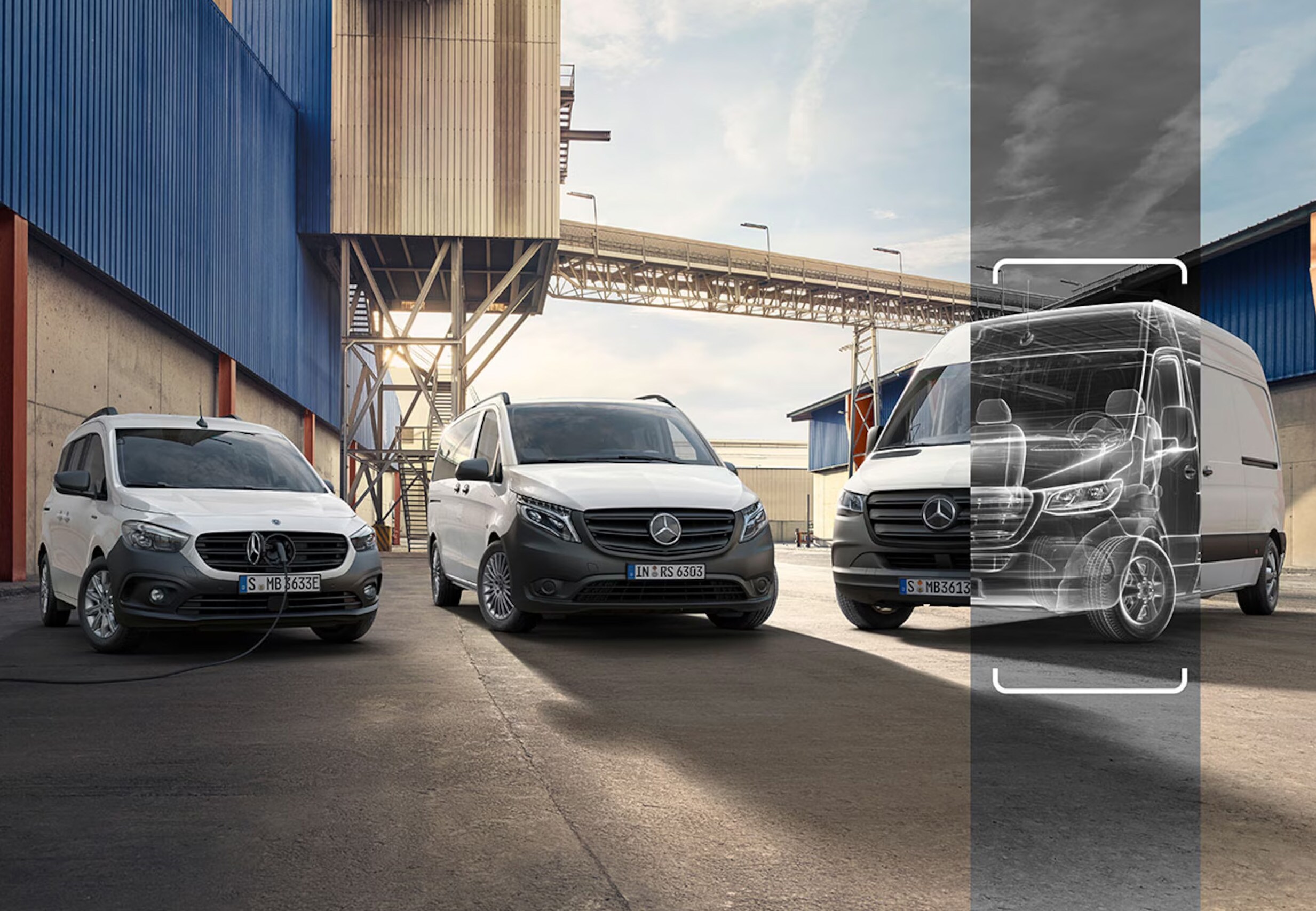 Trois utilitaires Mercedes-Benz, dont un modèle électrique en charge, devant un site industriel.