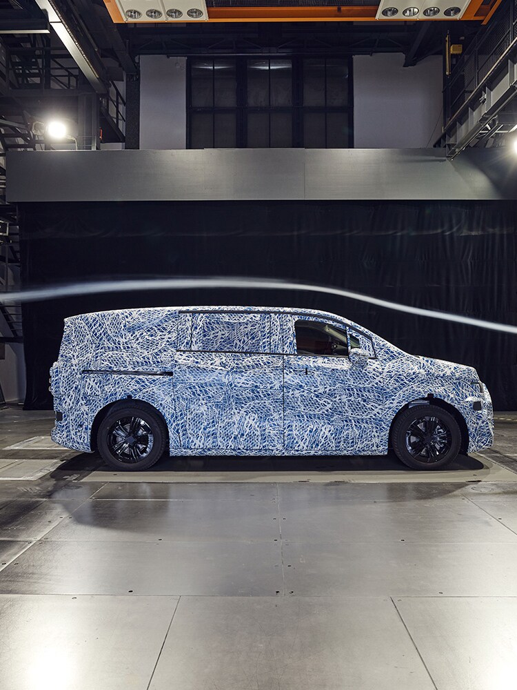 Prototype Mercedes-Benz camouflé vu de profil dans un centre de développement.