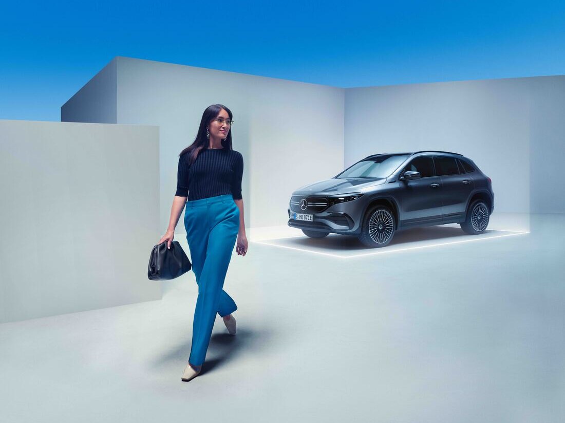 Une femme s'éloigne de sa Mercedes-Benz garée.
