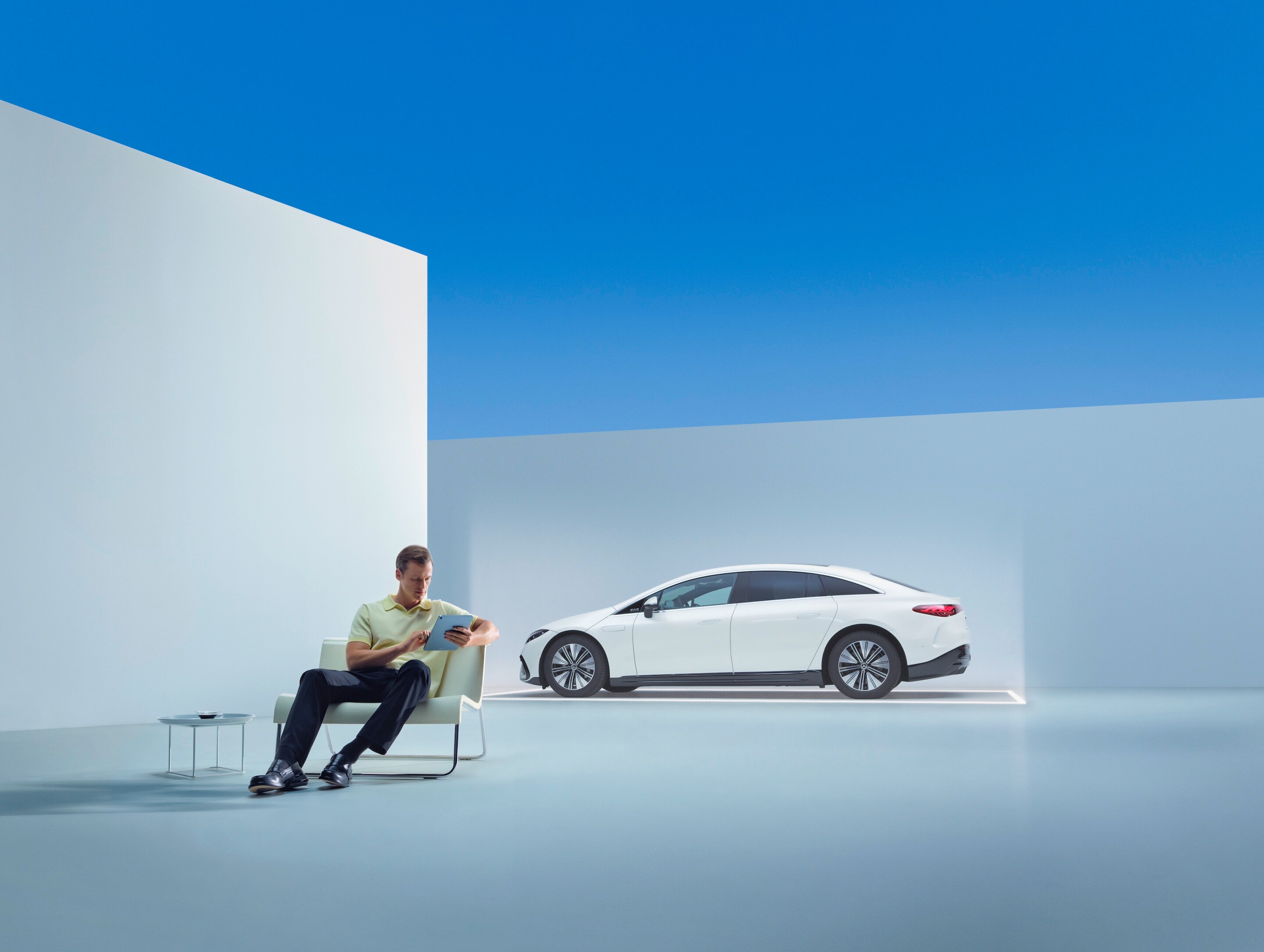 Un homme est assis devant sa Mercedes-Benz, son smartphone à la main
