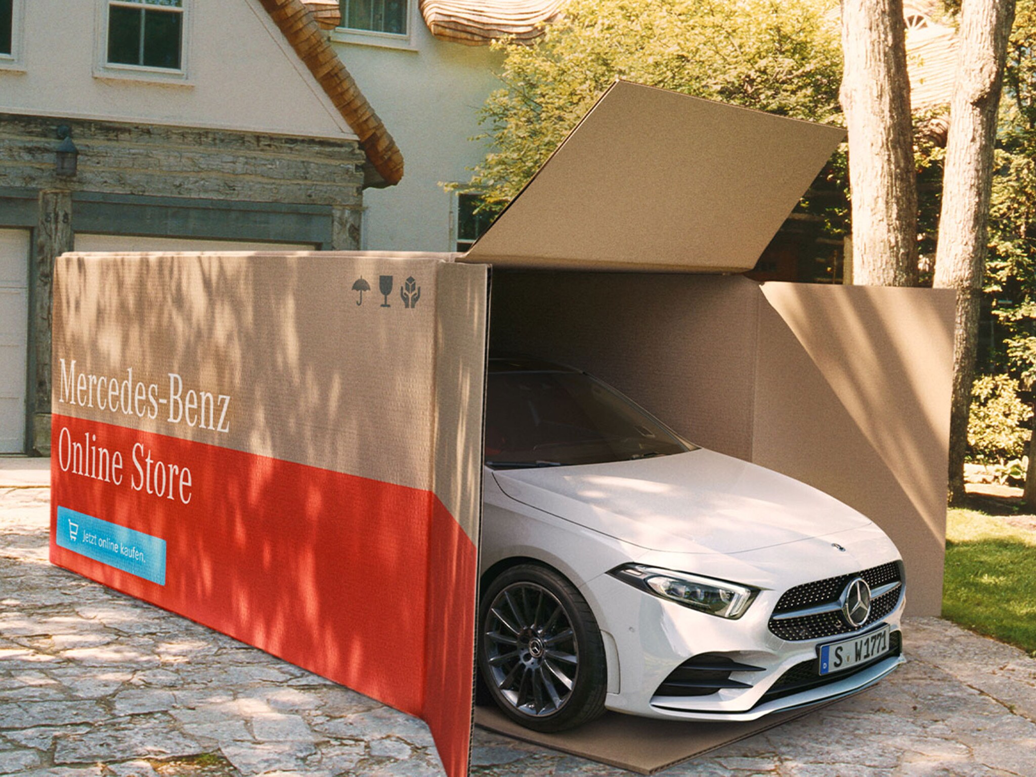 Mercedes-Benz Classe A blanche sortant d'une boîte Mercedes-Benz Online Store devant une maison.