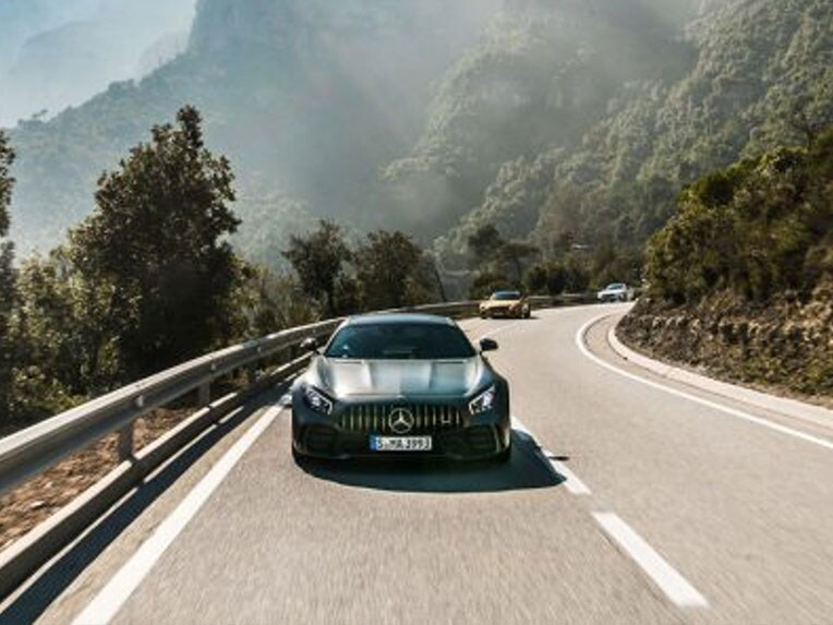 Une Mercedes-AMG GT R vue de face roulant sur une route.
