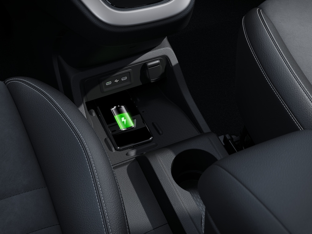L'image montre la console centrale du véhicule, plus précisément le tapis de recharge sans fil. Un smartphone est placé sur le tapis et est en cours de recharge.