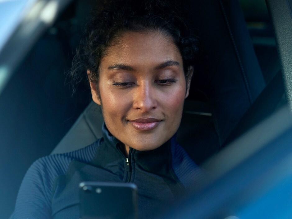 Personne assise à bord d'une Mercedes-Benz consultant son smartphone.