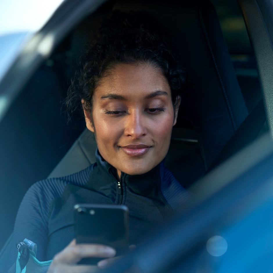 TVS Personne assise à bord d'une Mercedes-Benz consultant son smartphone.