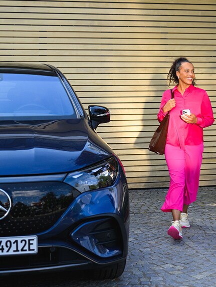 Image d'un couple au volant d'une Mercedes-Benz EQS en concession accompagné d'un distributeur.
