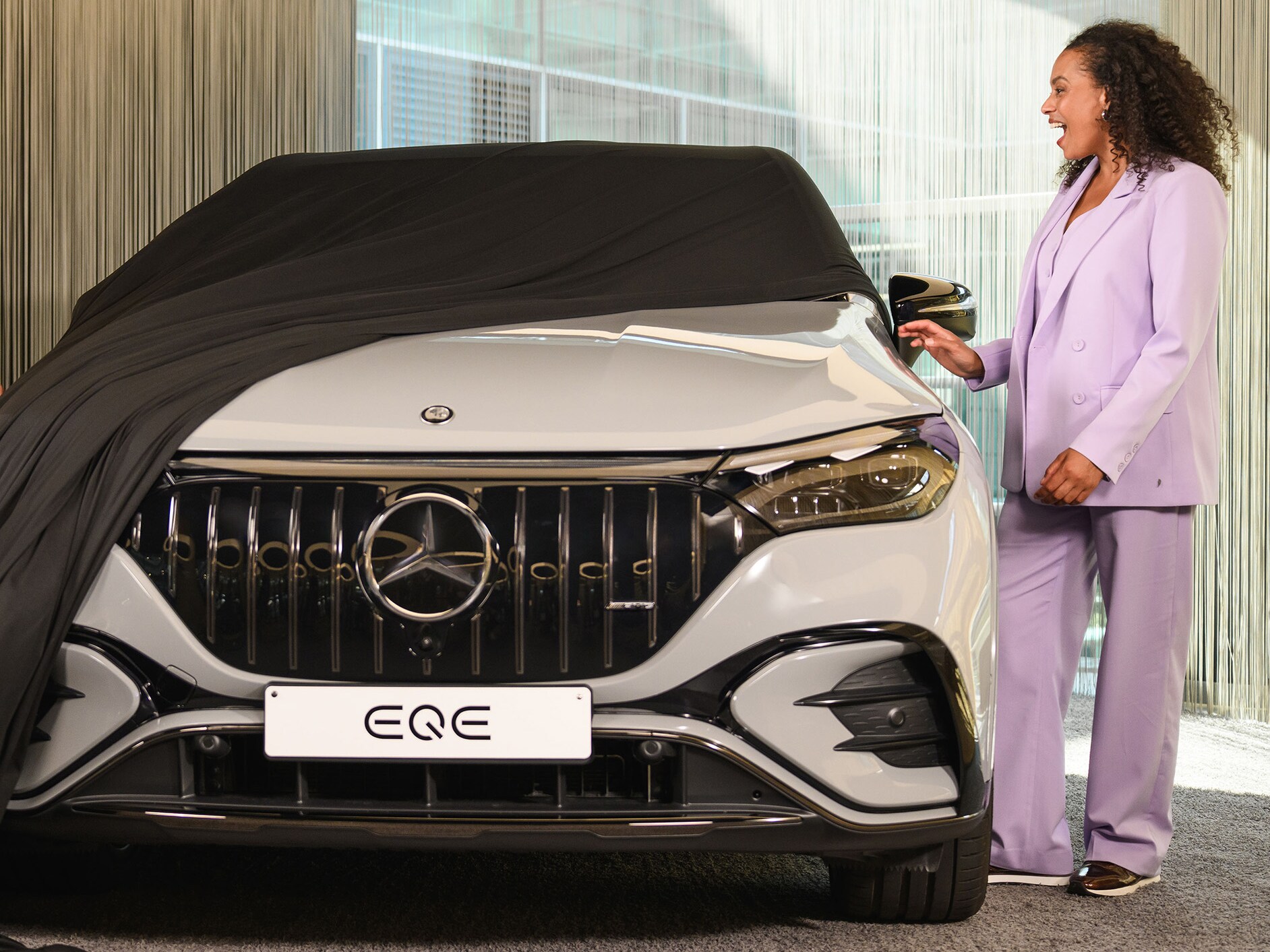 Femme découvrant une Mercedes-Benz EQE SUV en concession.