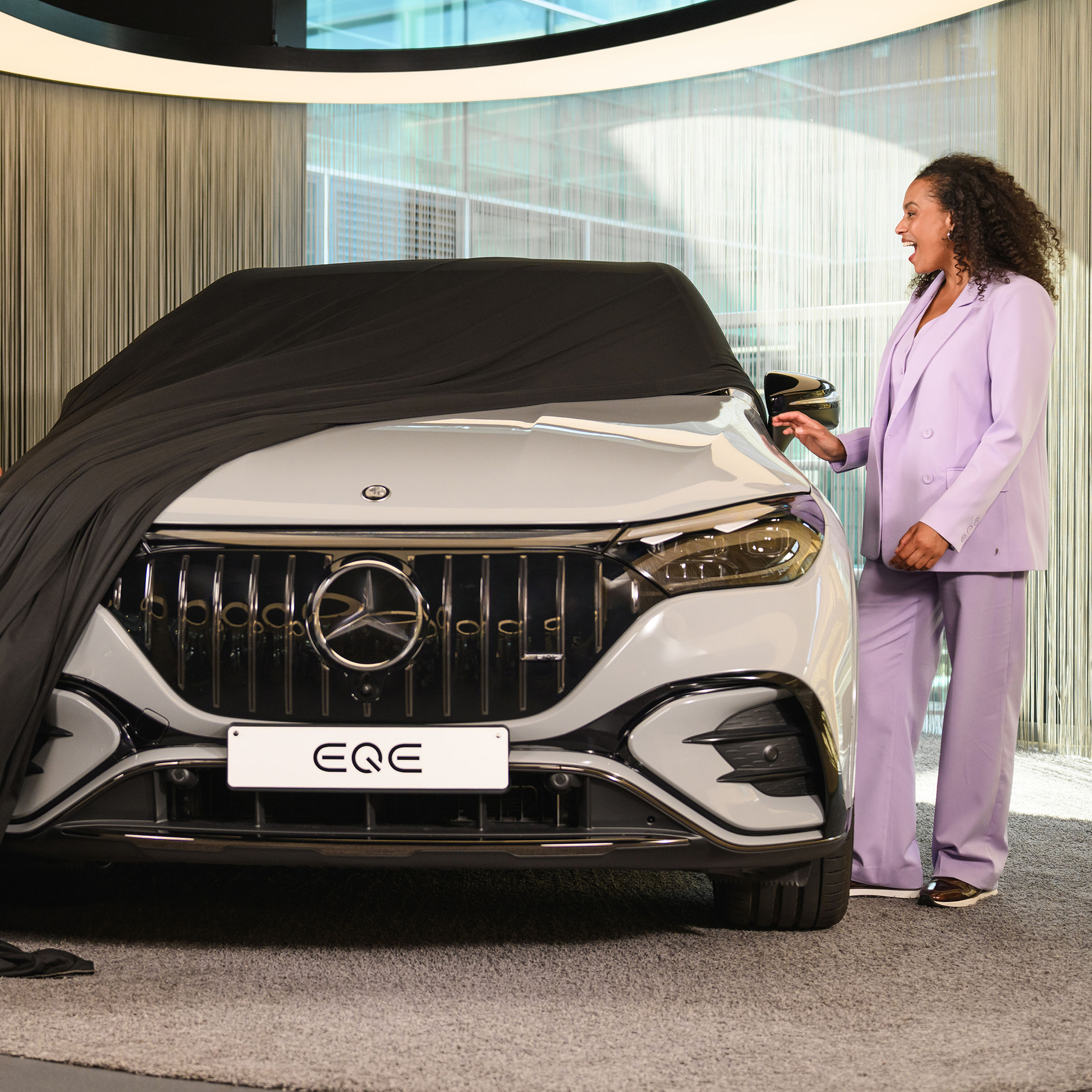 Mercedes-Benz EQS en concession Femme découvrant une Mercedes-Benz EQE SUV en concession.
