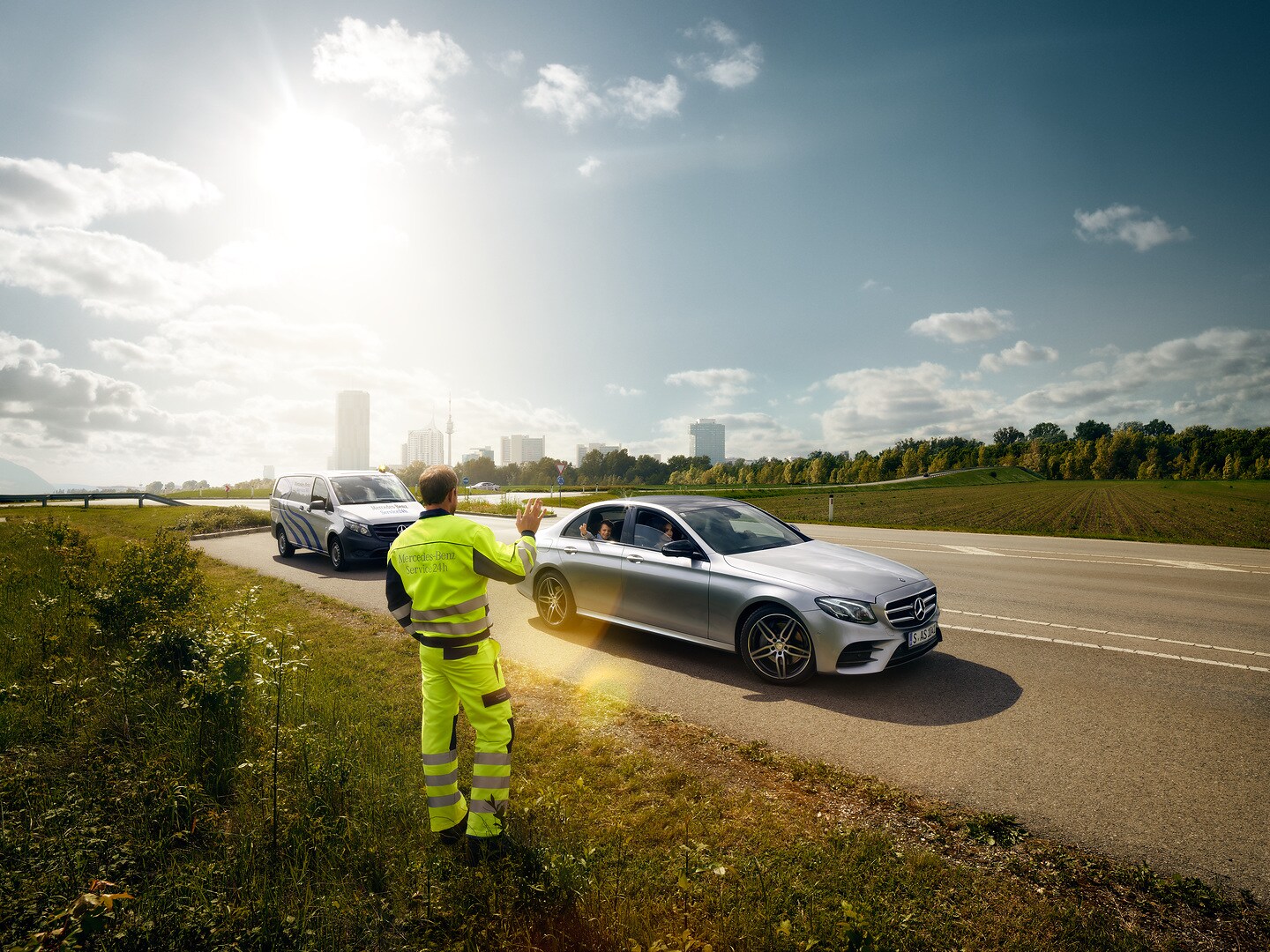 Un technicien de maintenance Mercedes-Benz fait signe à un enfant assis dans une Mercedes.