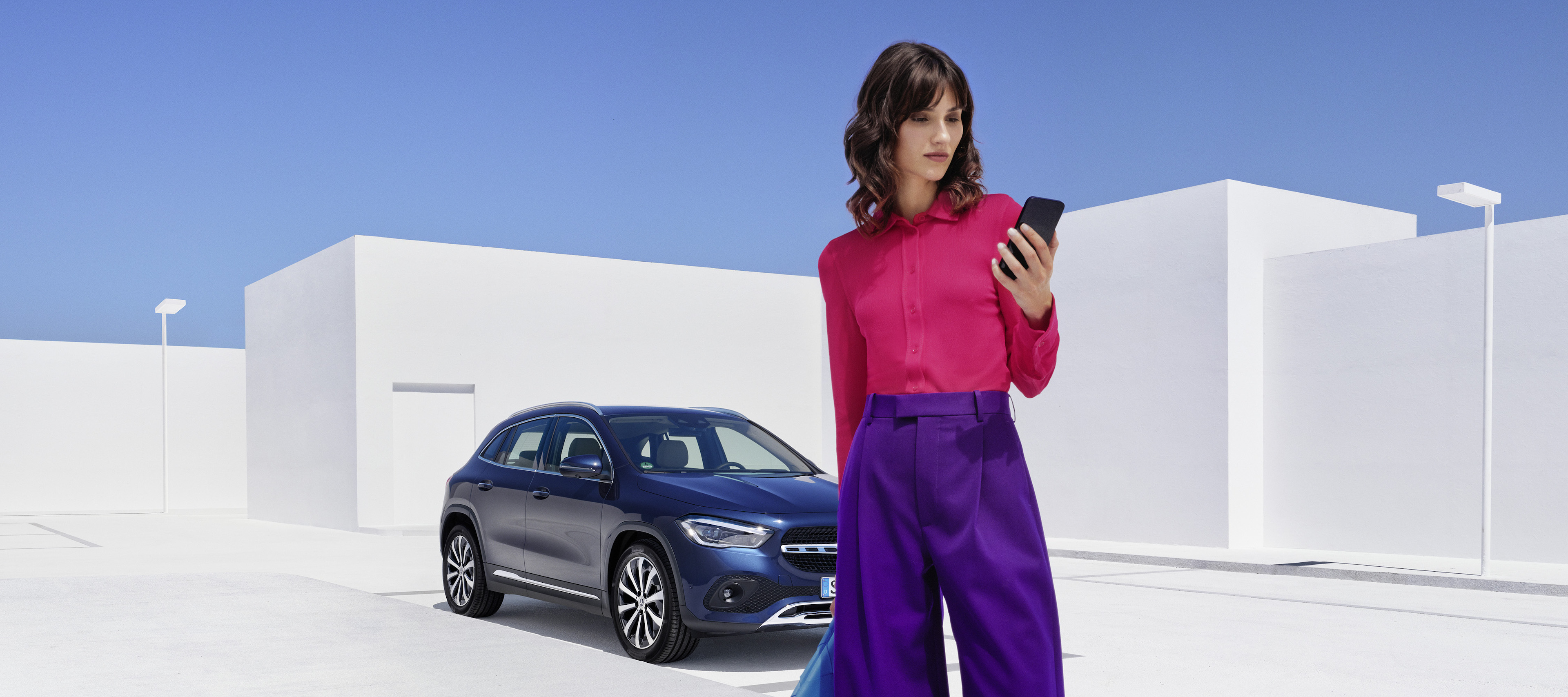 Montage et installation Mercedes-Benz Une femme se tient devant une Mercedes-Benz et consulte son smartphone.