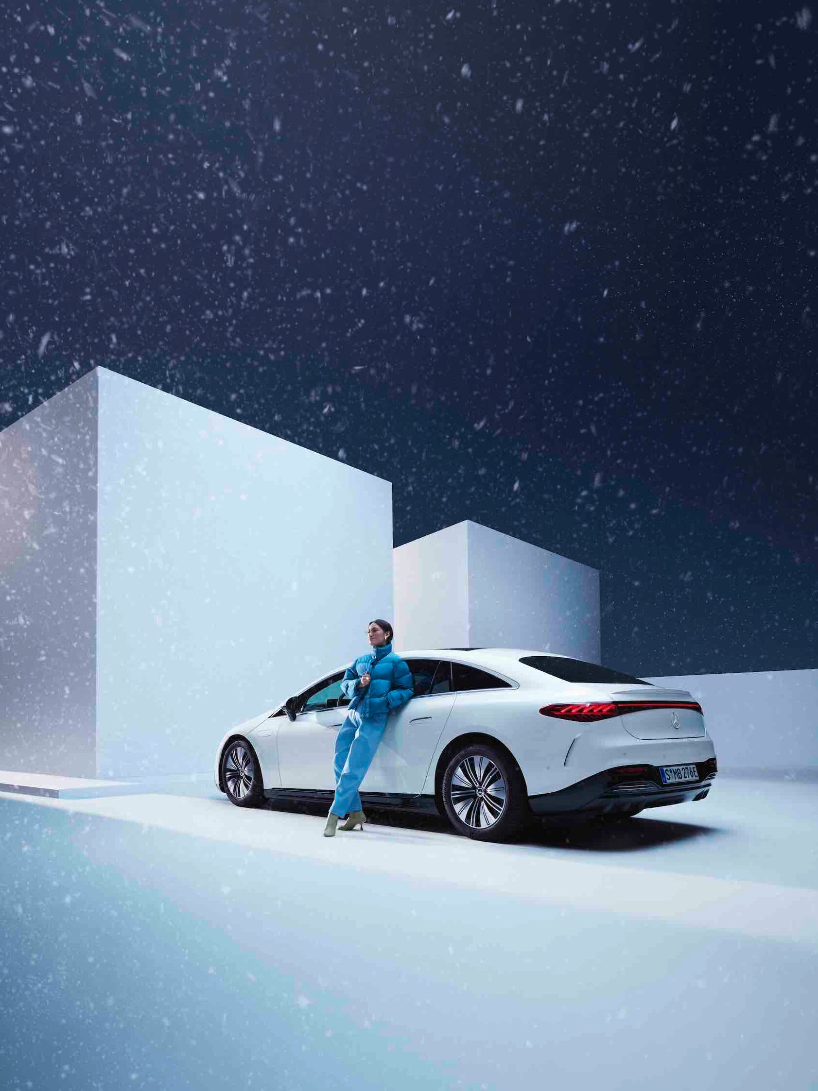 Une femme s’appuie contre sa Mercedes tandis qu’il neige.