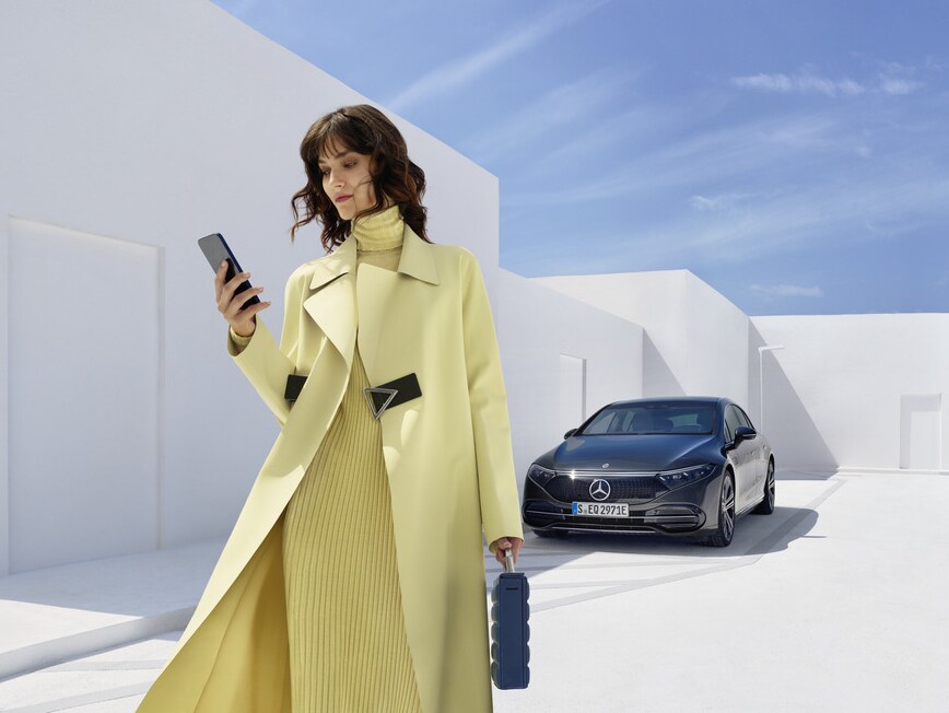 Une femme avec son téléphone alors qu'elle se tient devant une Mercedes-Benz.