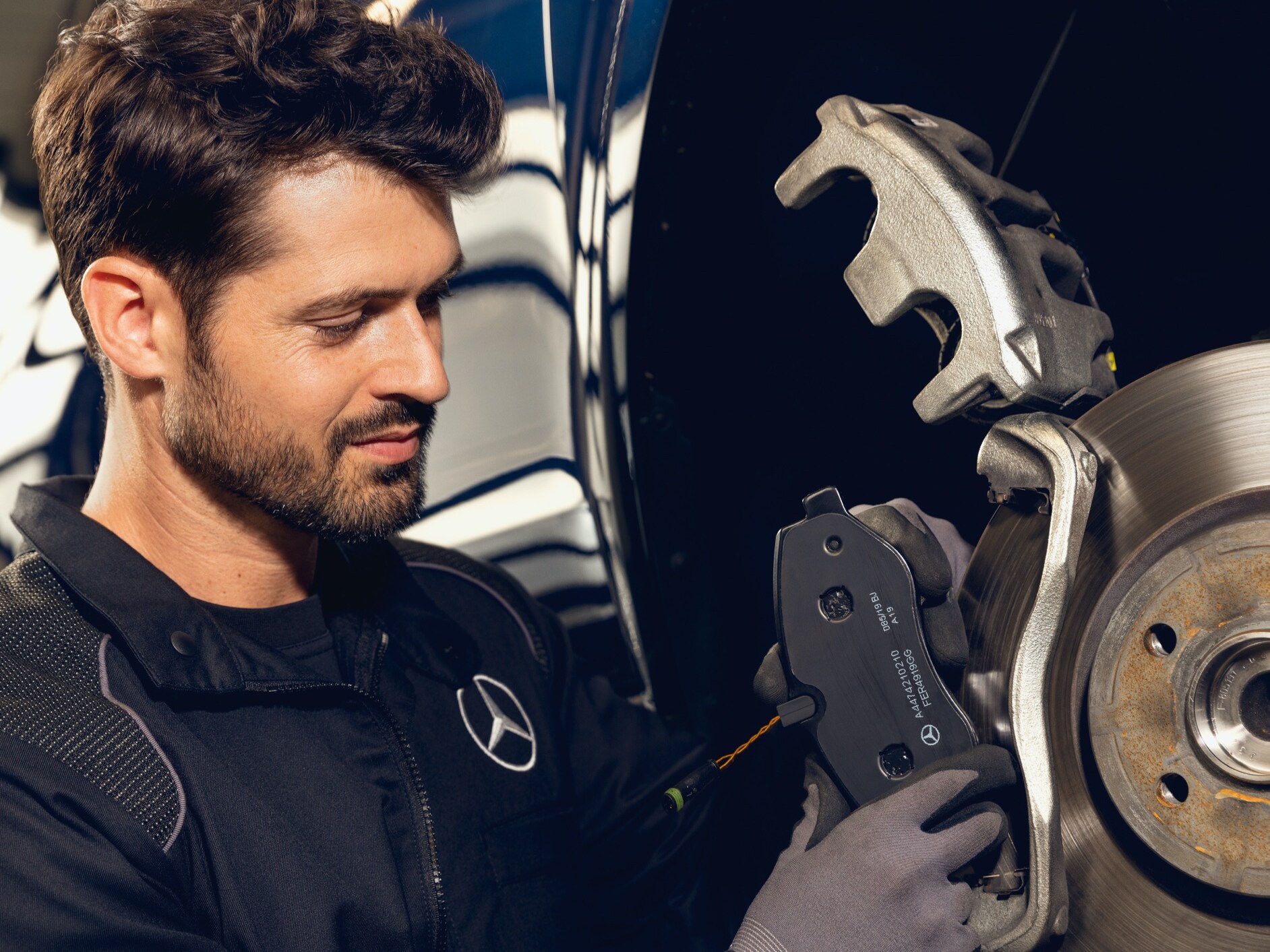 Une Mercedes-Benz stationnée devant quelques étagères où sont entreposées des roues.