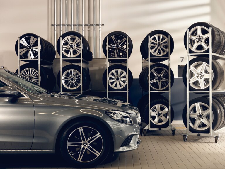 Une Mercedes-Benz stationnée devant quelques étagères où sont entreposées des roues.