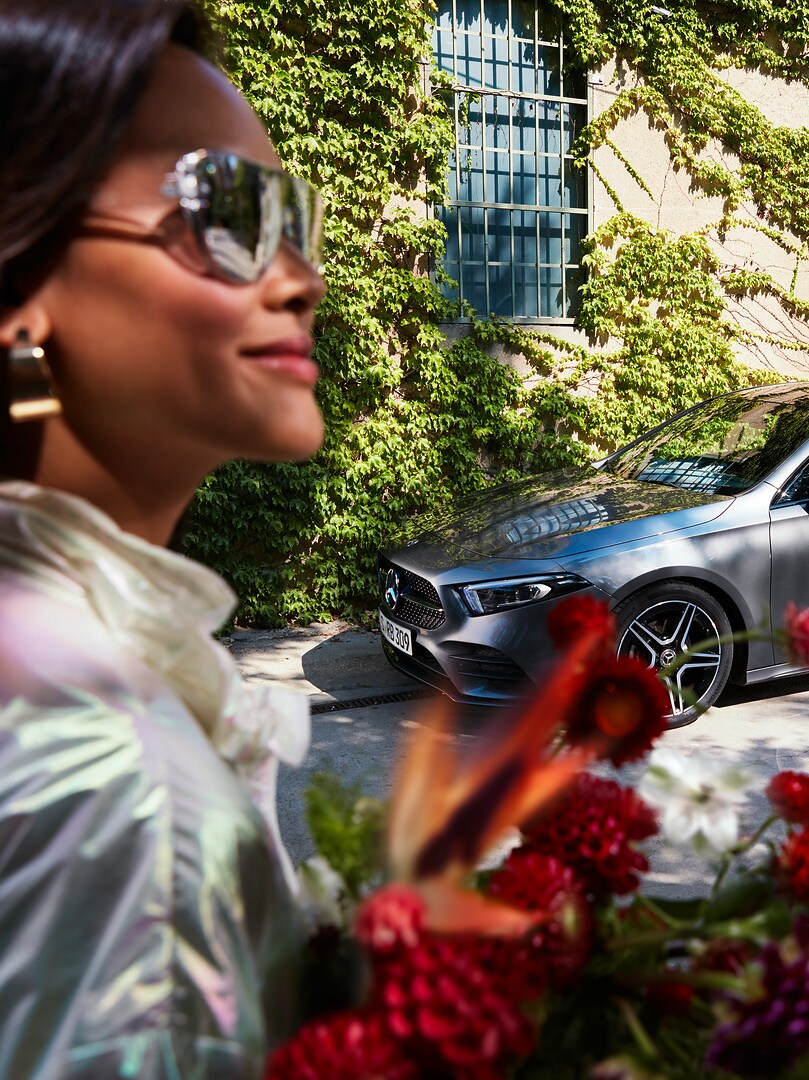 Des fleurs à la main, une femme détendue se dirige vers sa Mercedes entretenue.