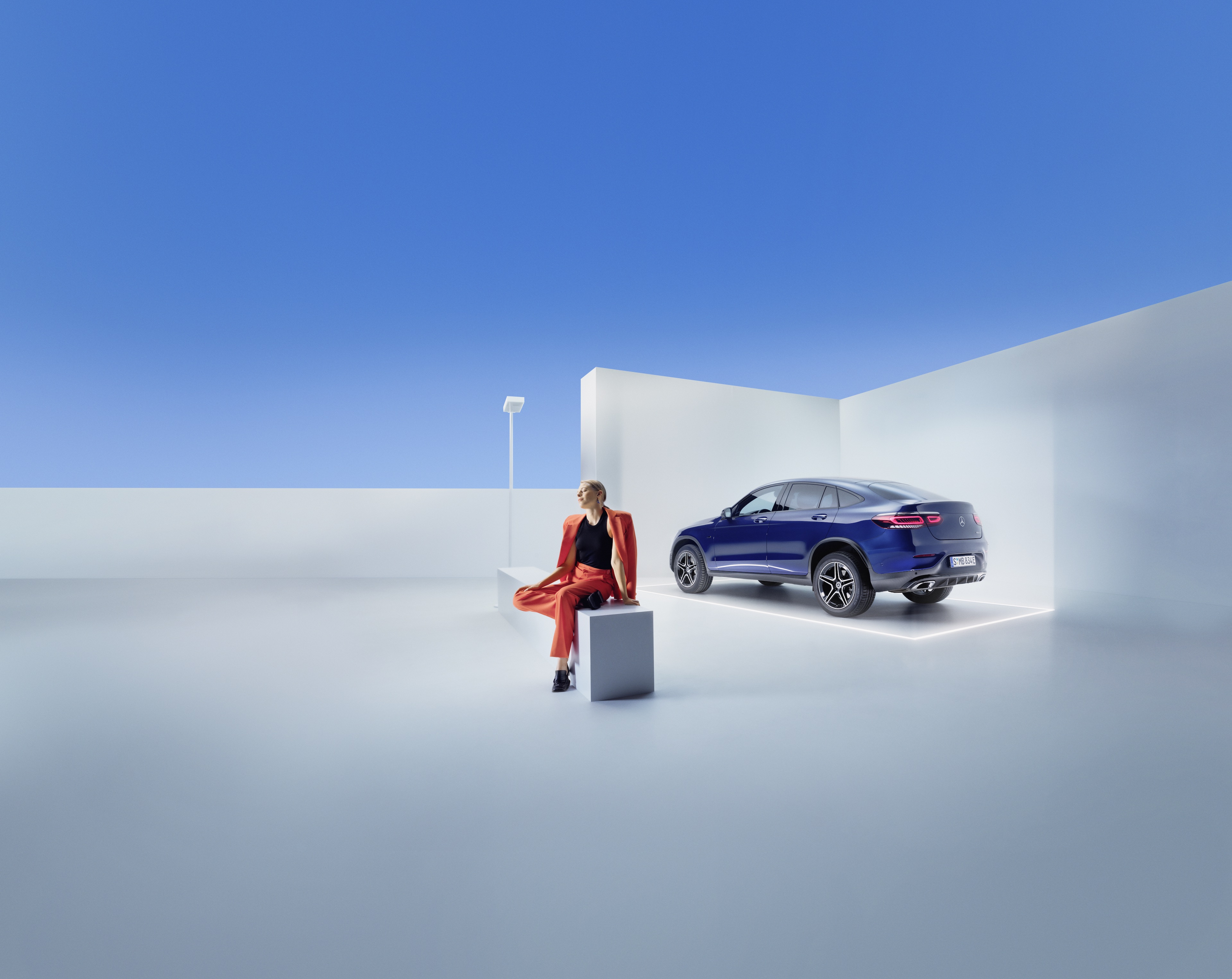 Contrats de service Mercedes-Benz Une femme est assise sur un banc devant une Mercedes-Benz.
