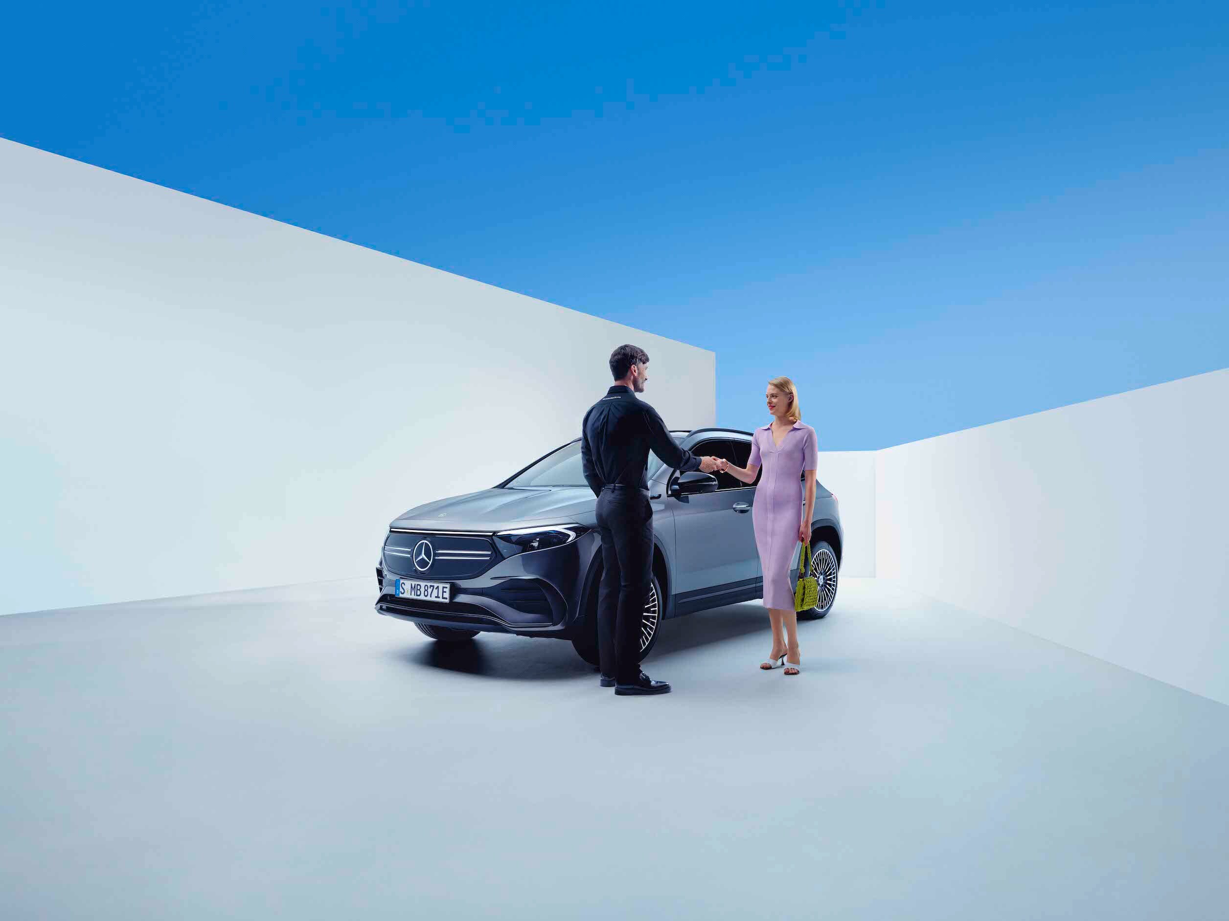 Un homme et une femme main dans la main devant une Mercedes-Benz.