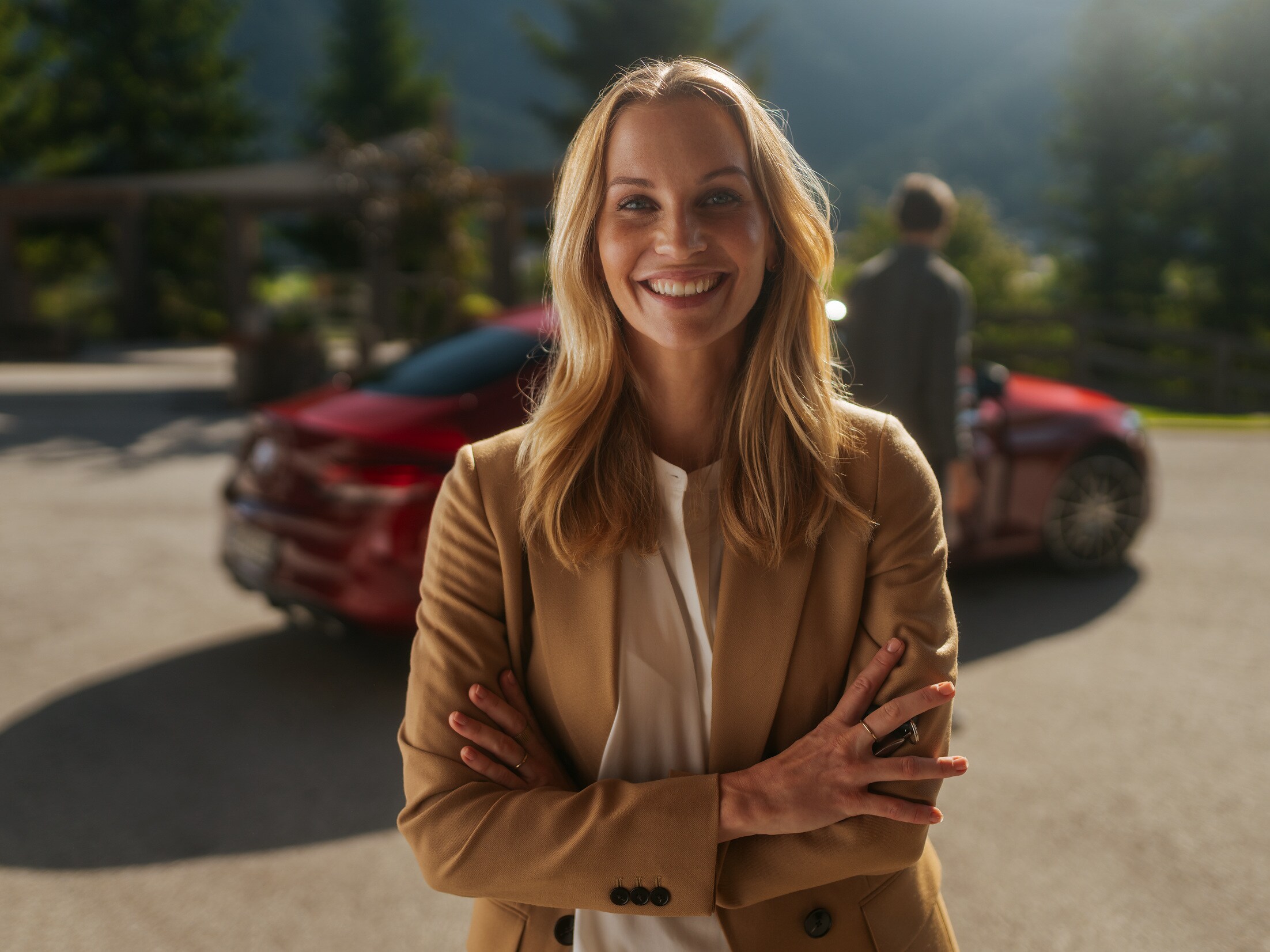 Une femme de bonne humeur est debout devant sa Mercedes.