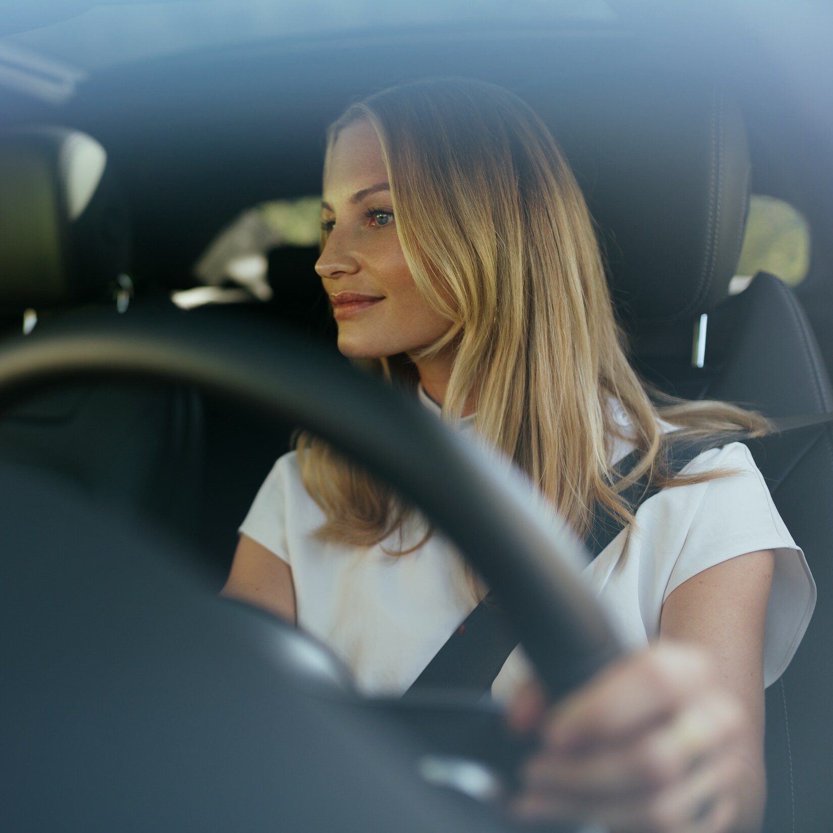 Une femme détendue au volant de sa Mercedes.