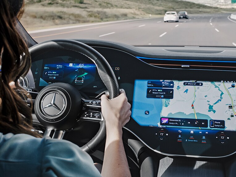 Une personne roule sur l'autoroute et se fait guider vers une place de stationnement par le système de navigation MBUX de Mercedes-Benz.