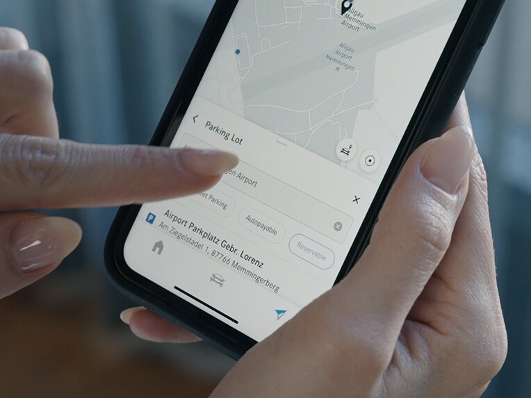 Une personne appuie sur son smartphone pour voir les prix des places de stationnement libre grâce à Off-Street Parking.