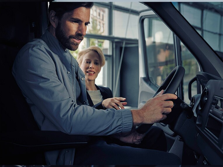Un homme est assis dans la Mercedes-Benz eSprinter et parle à un distributeur