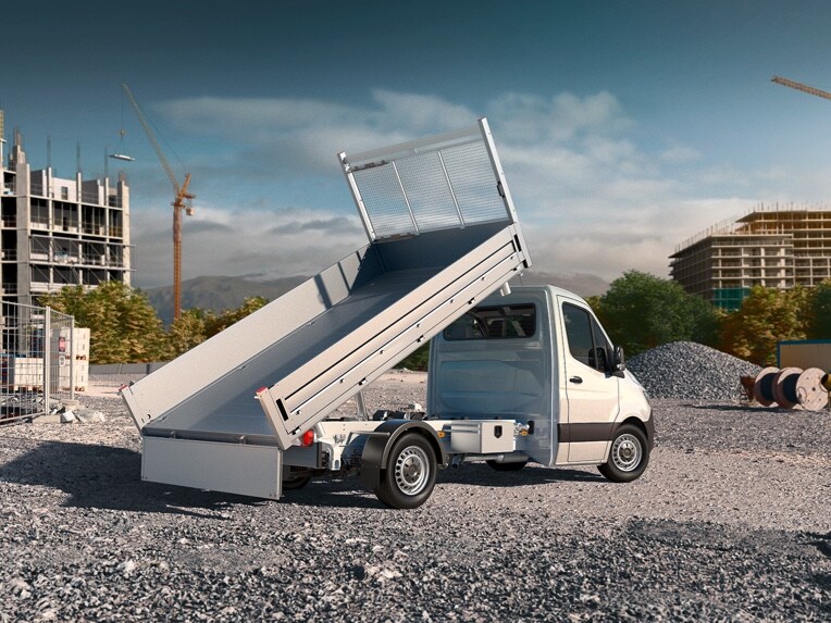 Un Sprinter à plateau Mercedes-Benz garé avec son plateau relevé en plein milieu d'un chantier de construction.