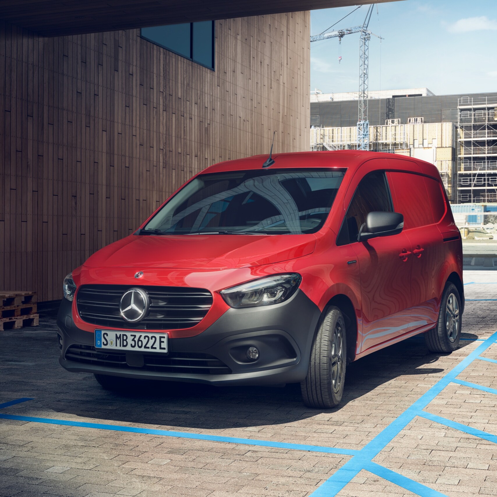 L'eCitan Fourgon, un utilitaire léger électrique de Mercedes-Benz, est garé devant une borne de recharge devant un bâtiment moderne.