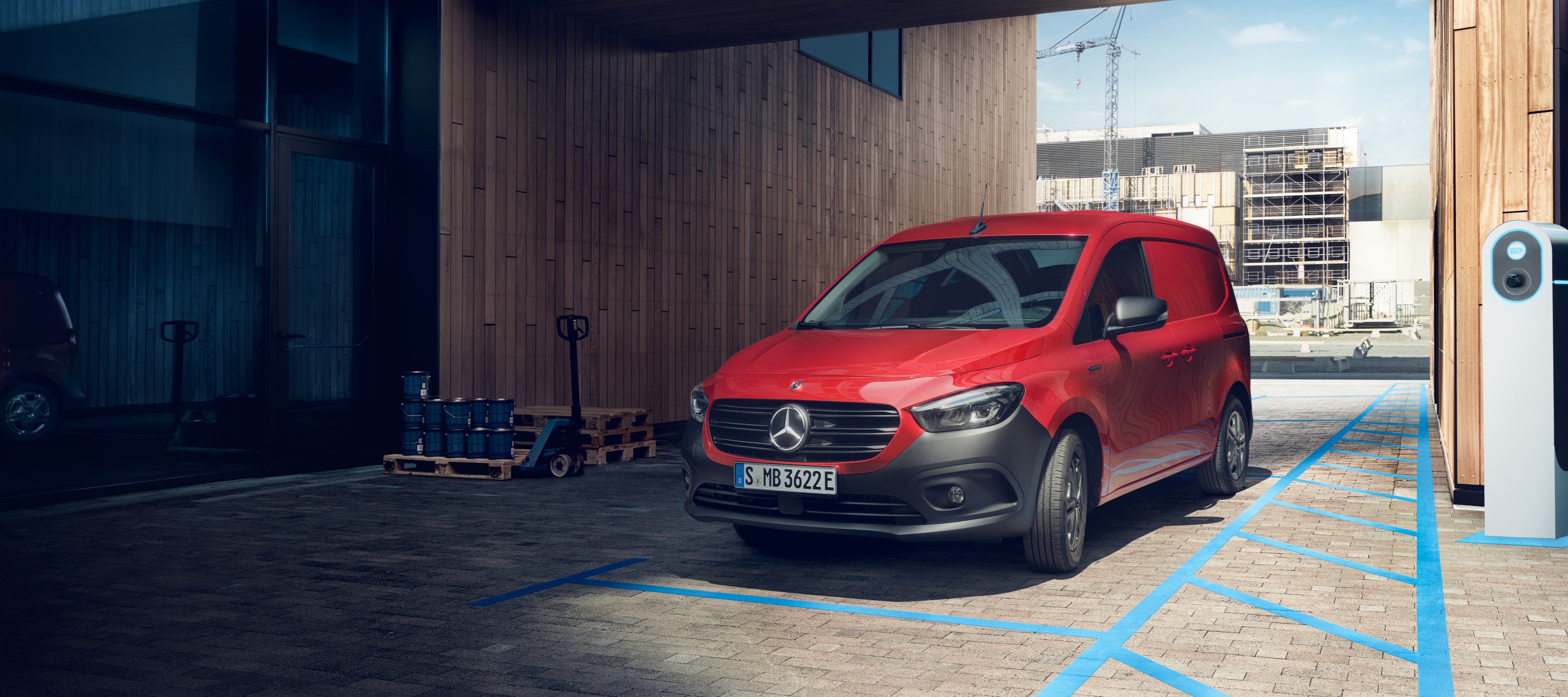 eCitan Fourgon | Utilitaires légers Mercedes-Benz L'eCitan Fourgon, un utilitaire léger électrique de Mercedes-Benz, est garé devant une borne de recharge devant un bâtiment moderne.