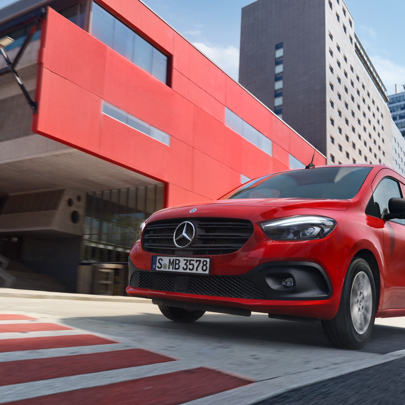 Les Mercedes-Benz eCitan Tourer et Fourgon sont garés devant un site à l'aspect industriel.