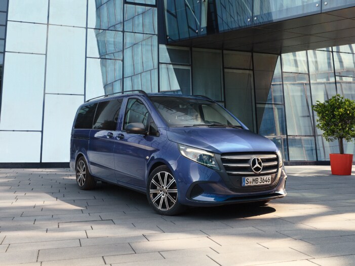 Mercedes-Benz Tourer bleu stationné devant un immeuble moderne.