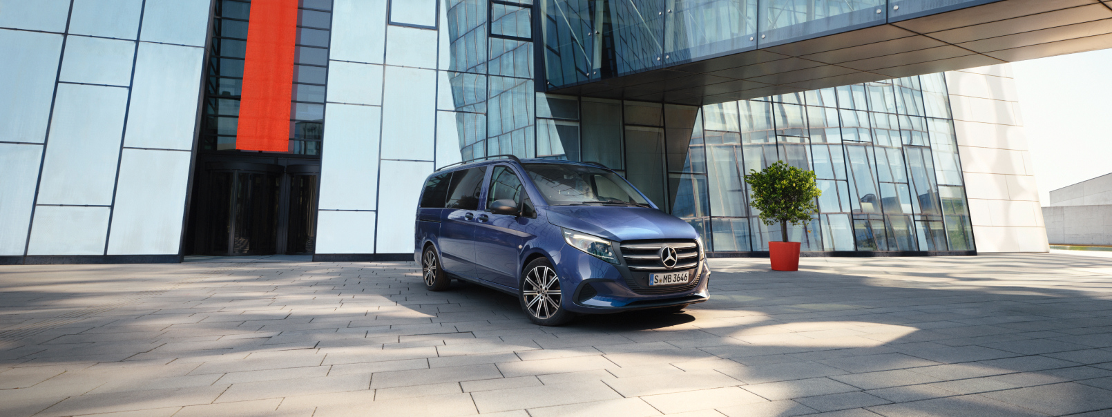 Gebrauchte BusinessVan von Mercedes-Benz Mercedes-Benz Tourer bleu stationné devant un immeuble moderne.