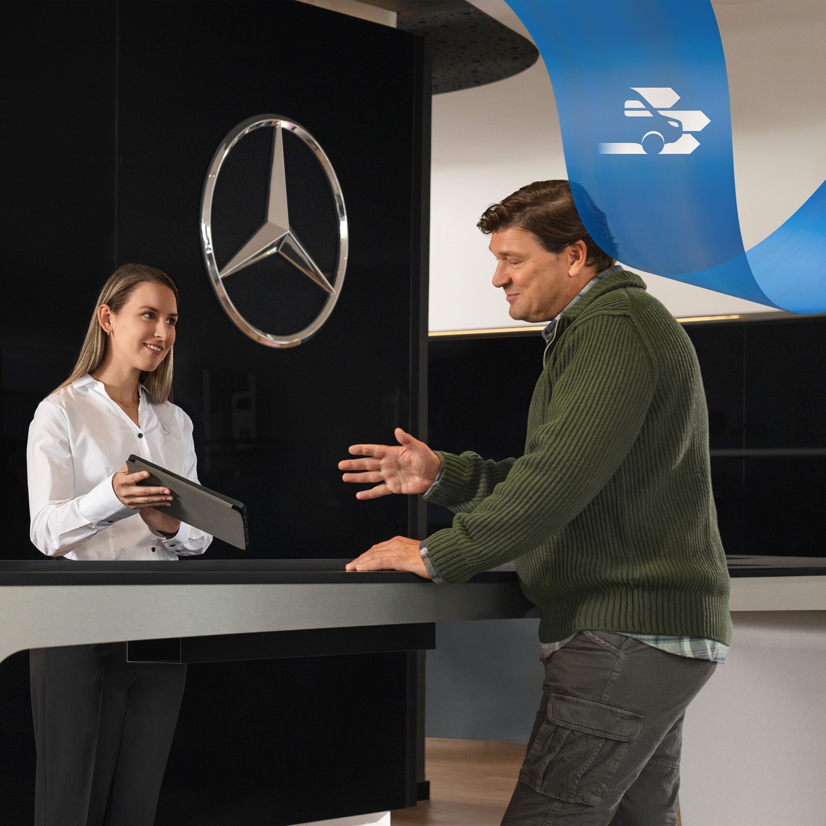 Un employé de Mercedes-Benz assiste un client debout à la réception.