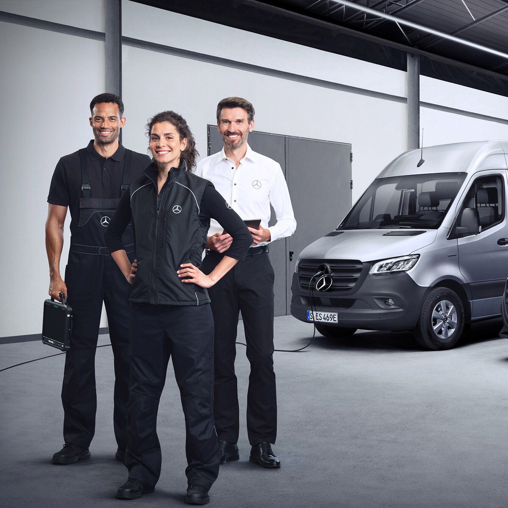 Trois collègues de l'équipe Mercedes-Benz Service devant une Mercedes-Benz eSprinter et une Mercedes-Benz eVito.
