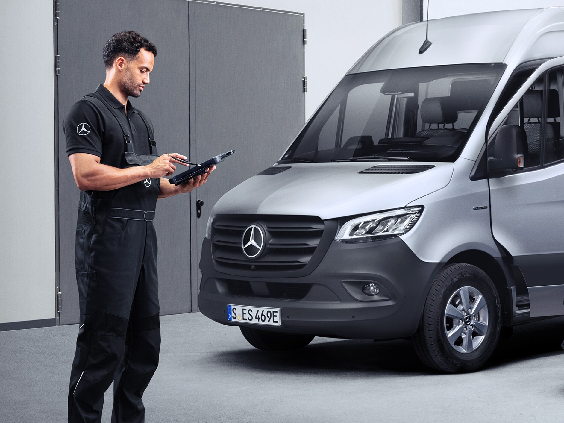 Un partenaire de service Mercedes-Benz consulte une tablette devant une Mercedes-Benz eSprinter.
