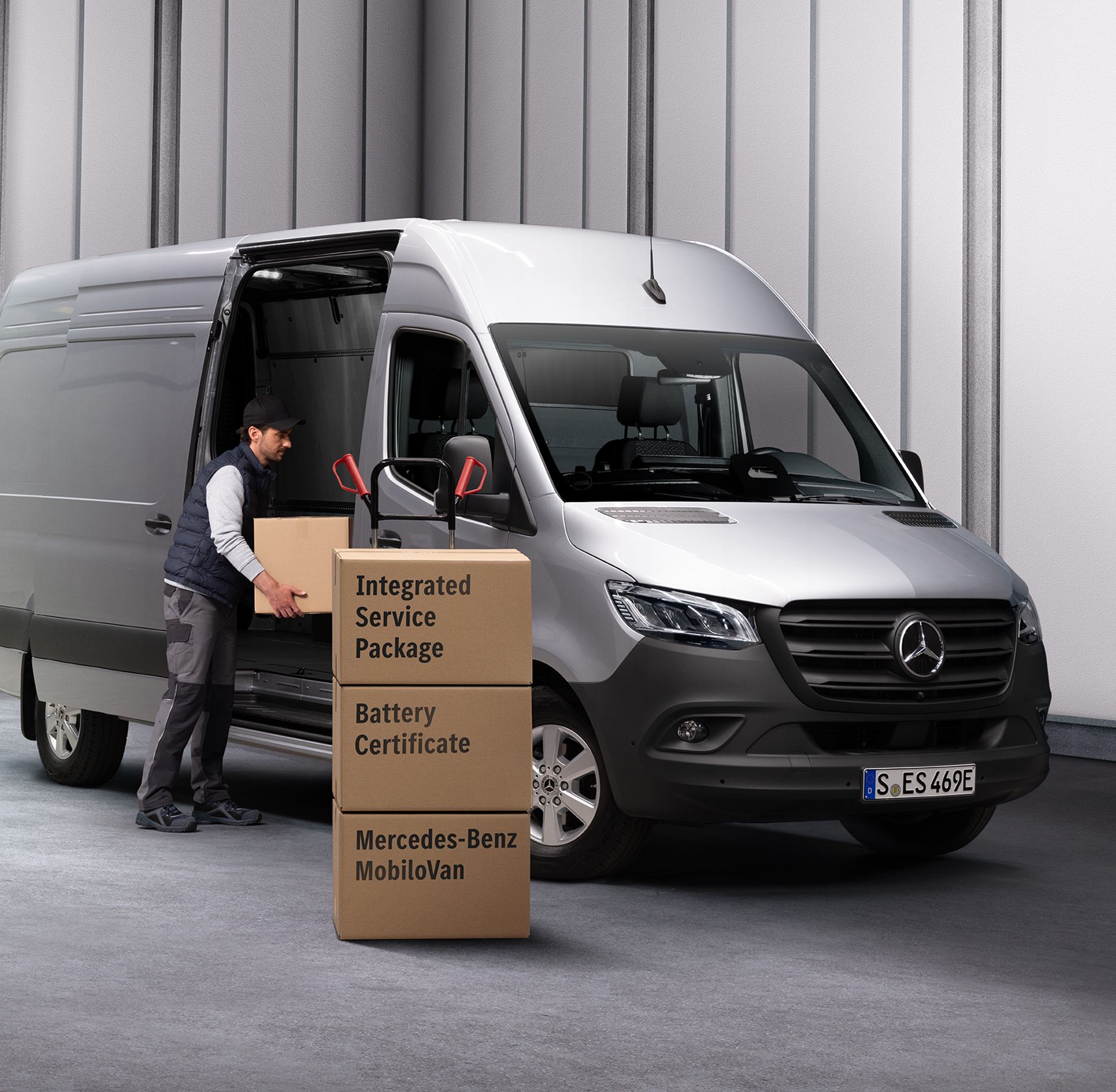 Partenaire de service Mercedes-Benz | Pack de services intégré Une personne déchargeant des cartons d'une Mercedes-Benz eSprinter. Trois boîtes sont empilées devant l'utilitaire léger. Les boîtes sont étiquetées avec les noms des produits de Mercedes-Benz Service.