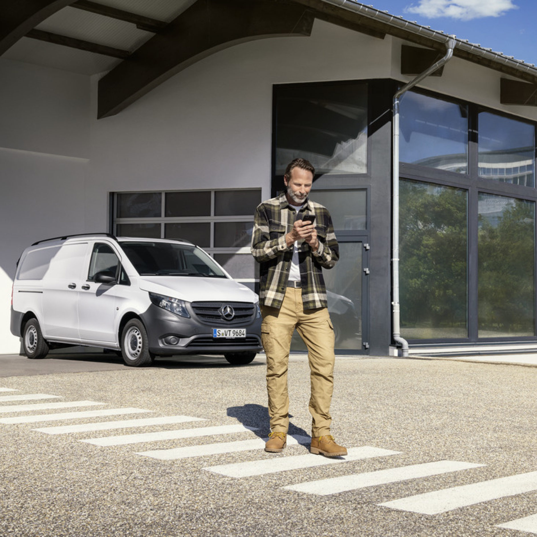 Mercedes-Benz Store | Offre digitale | Mercedes-Benz Une personne avec un smartphone devant un Mercedes-Benz Vito.