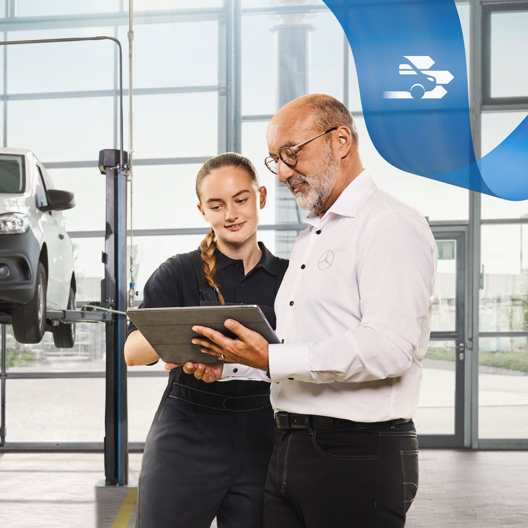 Deux employés discutent de l'entretien d'un véhicule utilitaire sur un utilitaire léger Mercedes-Benz sur cric dans l'atelier.