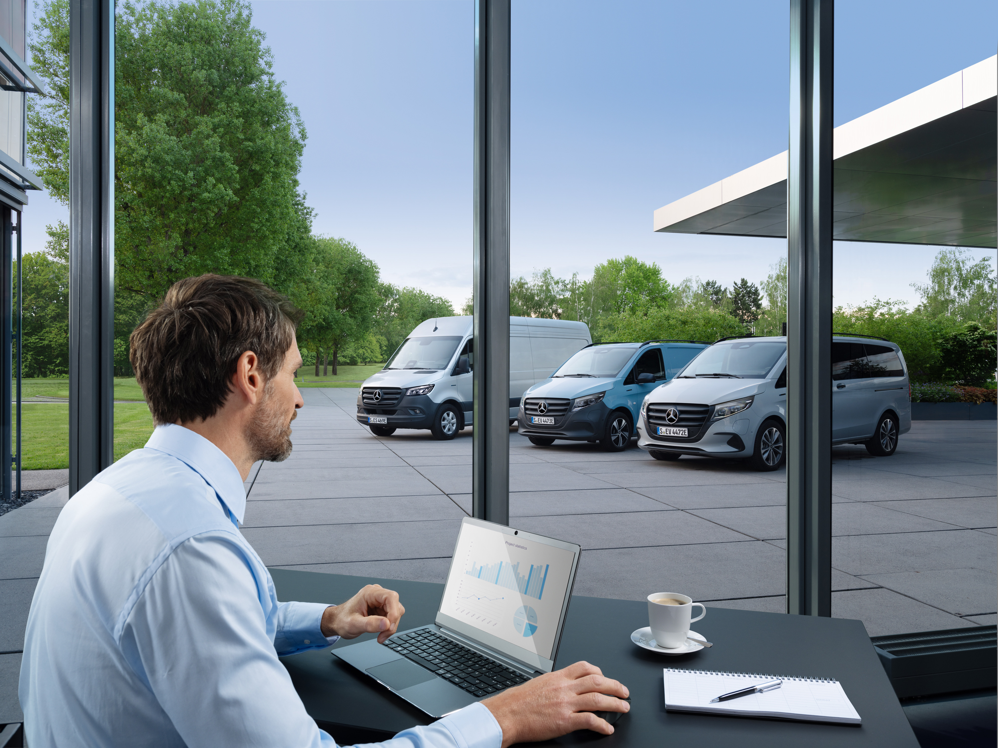 Mercedes-Benz | Technologie des utilitaires légers | Van Uptime Monitor Un homme surveille plusieurs utilitaires légers Mercedes-Benz stationnées à l'aide d'un ordinateur portable, symbole de la gestion numérique de la flotte.